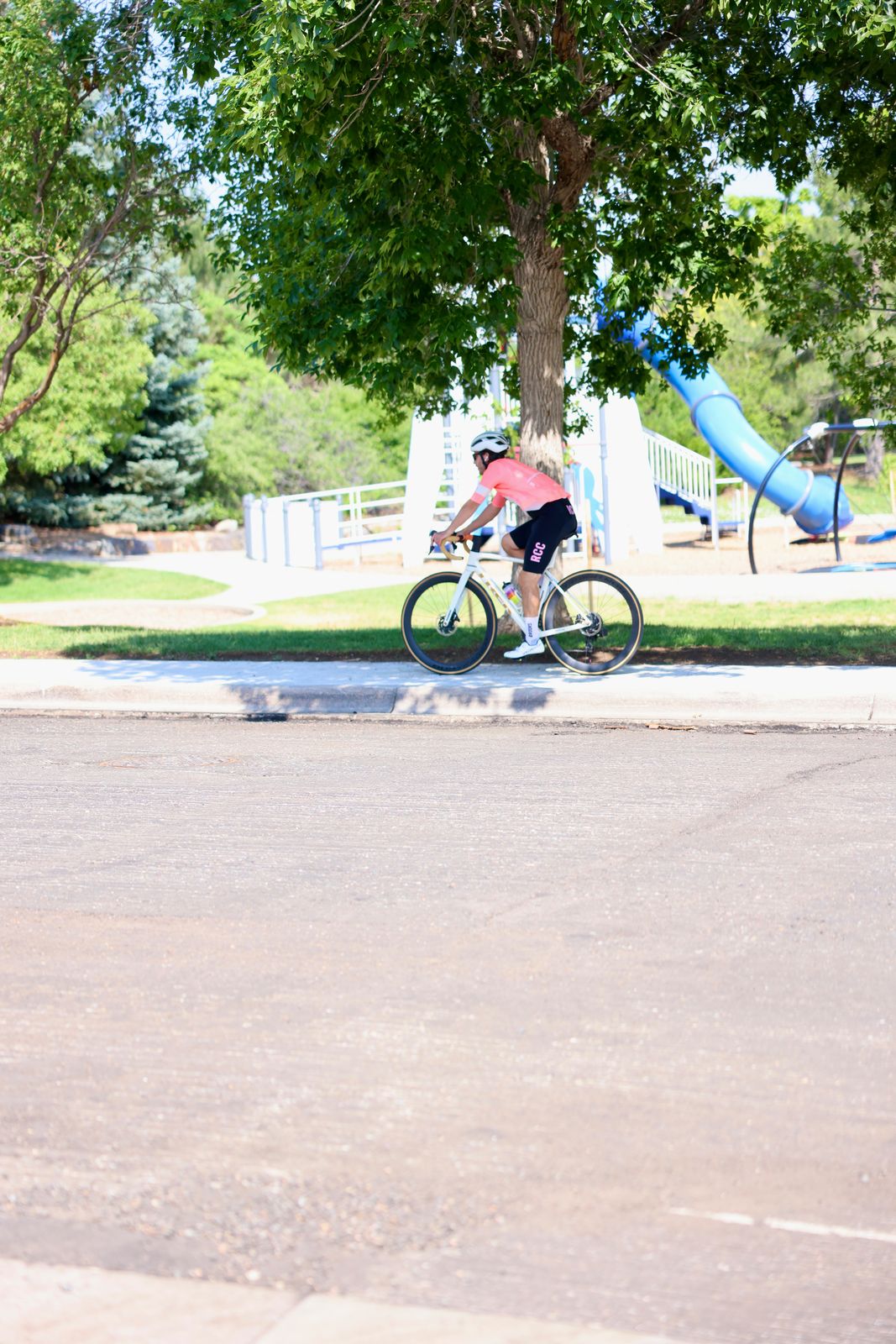 Carter Luense riding past the park playground in RCC kit