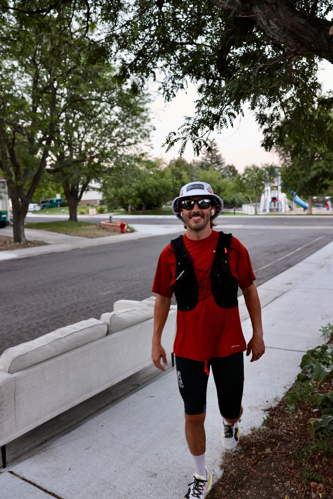 Carter Luense mid-run in vest and bucket hat, smiling, Westminster