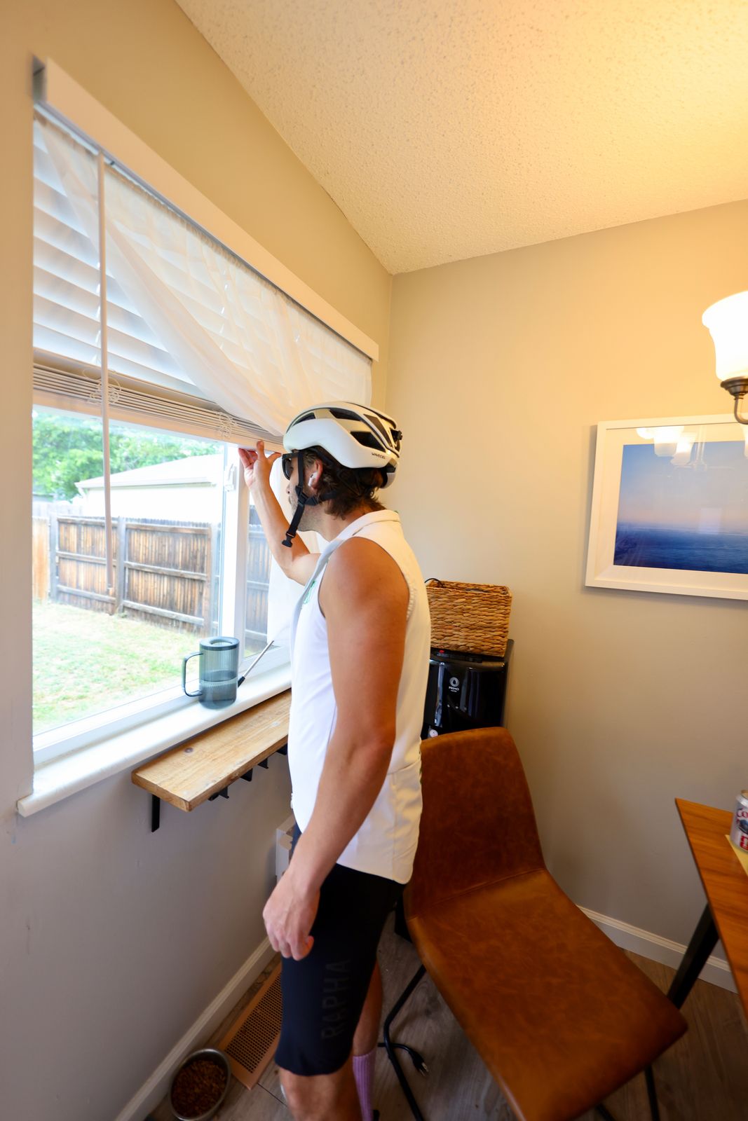 Carter Luense in helmet and gilet peeking out the kitchen window at the backyard