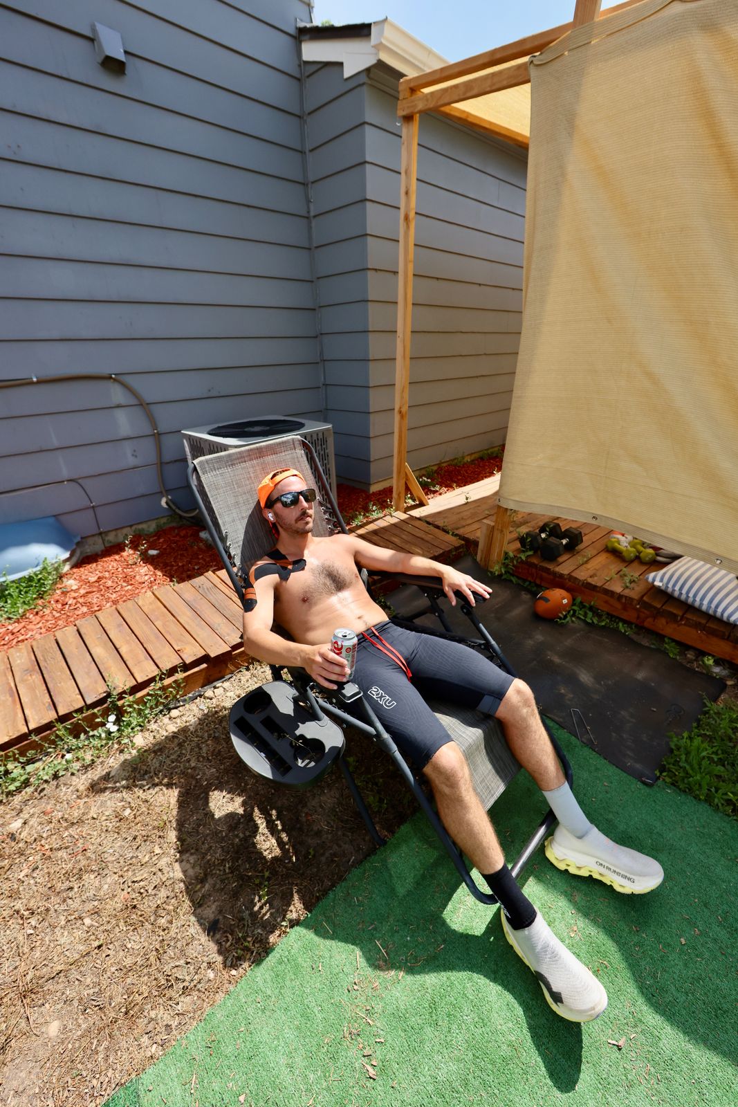 Carter Luense recovering in the backyard shade after a run, taped shoulder, feet up